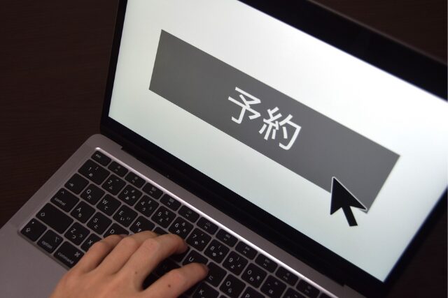 小浜島旅行のオンライン予約。ノートパソコンで「予約」ボタンをクリックしようとしている手元。